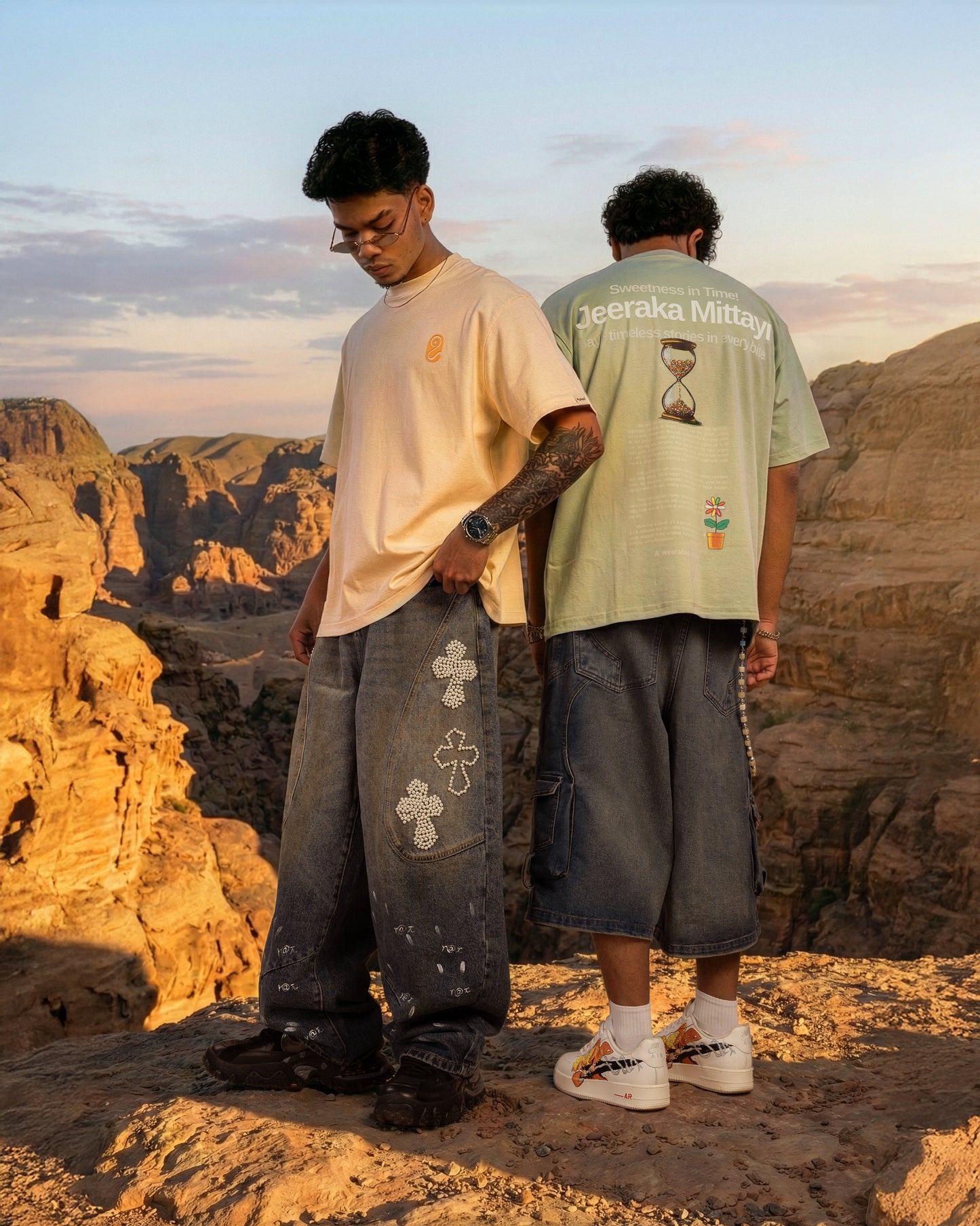 Two people standing in a desert landscape with mountains in the background.